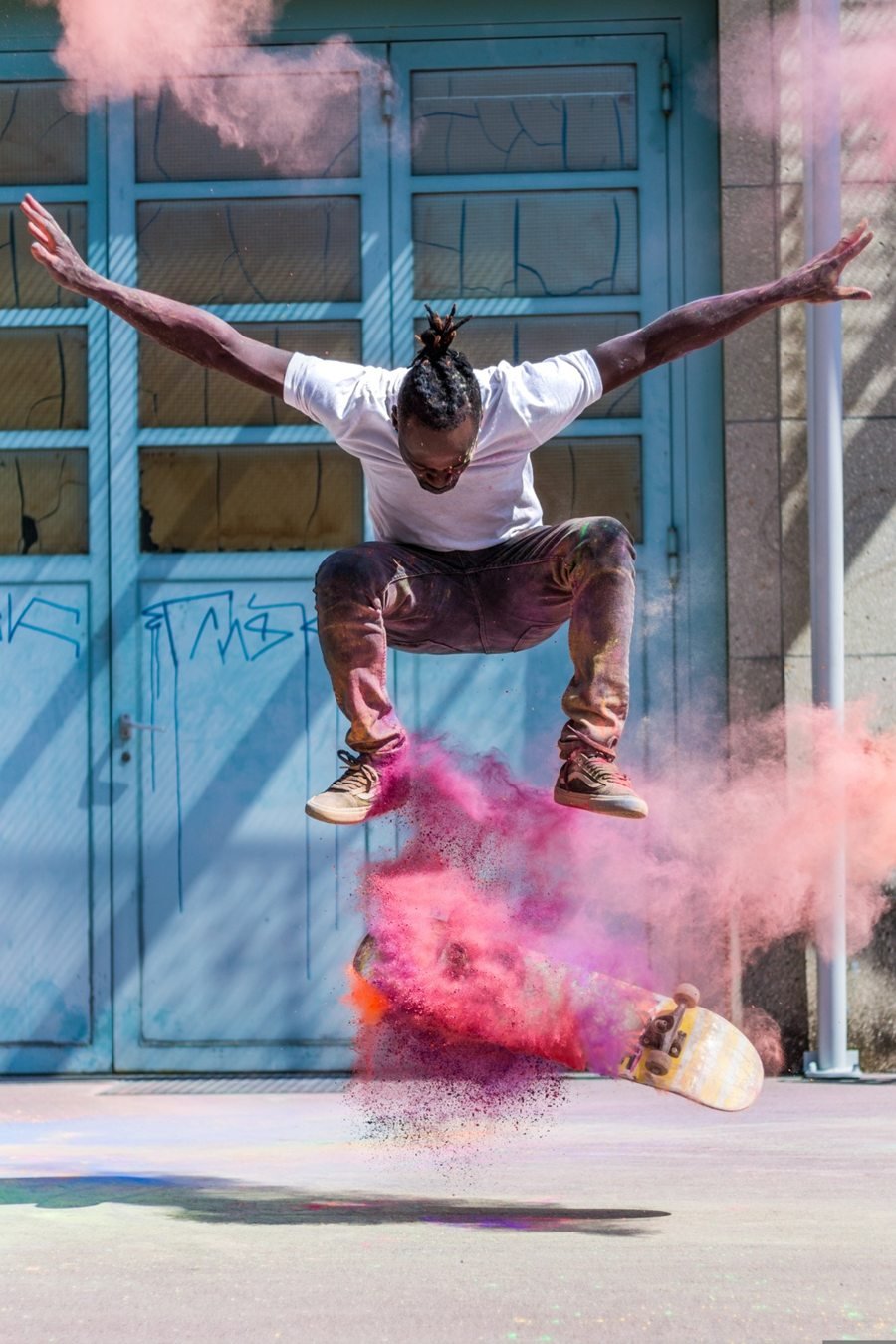 The original photo: a skateboarder in mid-air in front of pale blue doors, with pink powder bursting around the board.