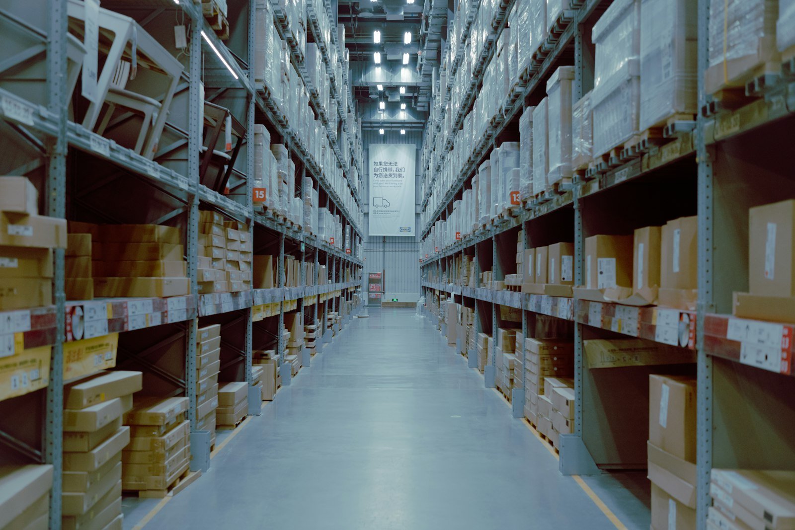 A long warehouse aisle between tall shelving stacked with boxes